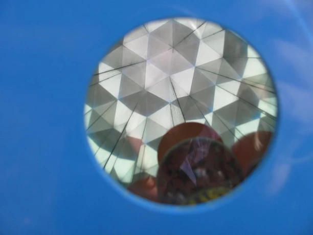 Nach dem Wippen rollen kleine Kugeln im Kaleidoskop auf Sie zu Durch eine blaue Öffnung blickt man auf einen Kristall-Effekt, der an ein Kaleidoskop erinnert.