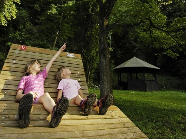 Das Kombiskop befindet sich direkt an einer Schutzhütte und Liegebank Zwei Kinder sitzen auf der Liegebank im Arboretum Bad Driburg.