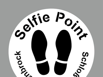 Kreisförmiges Schild mit der Aufschrift "Selfie Point Schloss Holte-Stukenbrock", darunter Fußabdrücke.