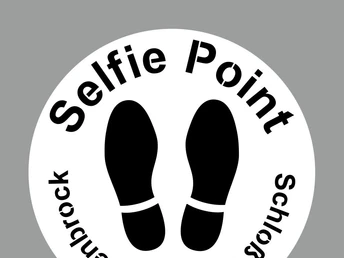 Selfie-Point SHS Schablone Kreisförmiges Schild mit der Aufschrift "Selfie Point Schloss Holte-Stukenbrock", darunter Fußabdrücke.