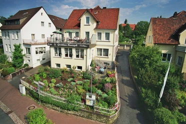 Gästehaus Havergoh mit gepflegtem Garten und Balkon, umgeben von weiteren Wohnhäusern.