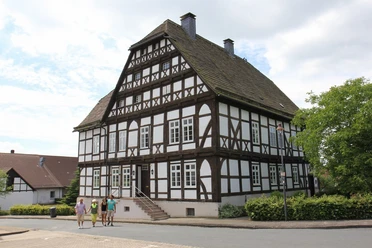 Das Priorhaus am Kloster Falkenhagen Fachwerkhaus mit steilem Satteldach und Sprossenfenstern, umgeben von Gehwegen und Vegetation.