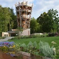 Baumwipfelpfad Bad Iburg Holzturm des Baumwipfelpfads Bad Iburg, umgeben von gepflegten Gärten und üppiger Vegetation.
