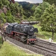 Modellbundesbahn Dampflokomotive Baureihe 44 Dampflokomotive der Baureihe 44 fährt durch eine modellierte Landschaft mit Bäumen und Hügeln.