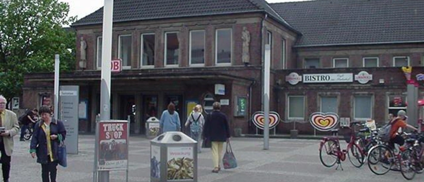 Bahnhof Rheine Backsteingebäude des Rheiner Bahnhofs mit Passanten und geparkten Fahrrädern vor dem Eingang.