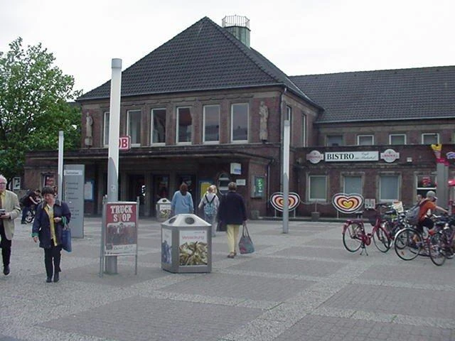 Bahnhof Rheine Backsteingebäude des Rheiner Bahnhofs mit Passanten und geparkten Fahrrädern vor dem Eingang.
