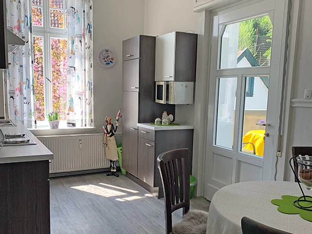 Küche Garden Apartment Helle Küche mit Esstisch und Stühlen, Holzschränken, großem Fenster und Glastür zum Garten.