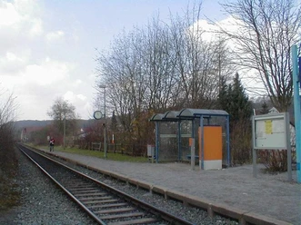 Bahnhof Westheim Kleiner Bahnhof mit einfachem Bahnsteig, Wartehäuschen, Gleisen und umliegenden Bäumen im Hintergrund.