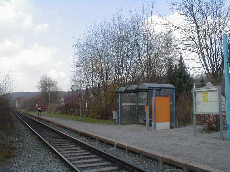 Bahnhof Westheim Kleiner Bahnhof mit einfachem Bahnsteig, Wartehäuschen, Gleisen und umliegenden Bäumen im Hintergrund.