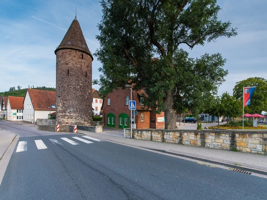 Dechenheim Lügde und Wehrturm Der mittelalterliche Wehrturm mit Fachwerkhäusern im Hintergrund, umgeben von einer Straße.