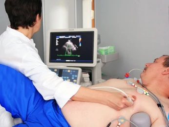 Ein Arzt führt eine Ultraschalluntersuchung des Herzens bei einem liegenden Patienten durch.