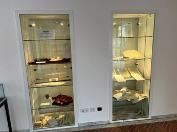 Dauerausstellung Susanna Abraham Zwei beleuchtete Glasvitrinen präsentieren historische Dokumente, Objekte und Schriften auf Regalböden.