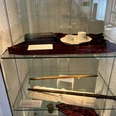 Kunstvoll arrangierte Ausstellungsstücke in einer Vitrine, darunter Teetassen und historische Accessoires.