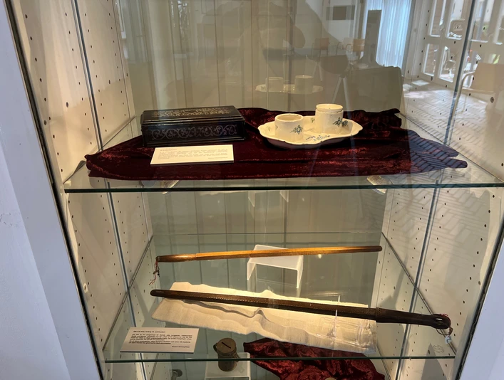 Kunstvoll arrangierte Ausstellungsstücke in einer Vitrine, darunter Teetassen und historische Accessoires.