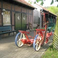 Landmaschinenmuseum Hörstel Rote, antike Pflugmaschine auf gepflastertem Hof vor einem Fachwerkgebäude mit grünen Türen.