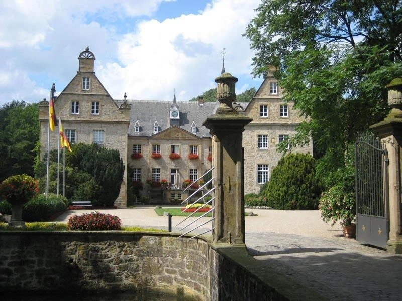 Wasserschloss Surenburg Historisches Wasserschloss Surenburg umgeben von Gärten, mit steinernem Tor und verzierter Fassade.