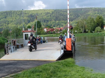 Gierseilfähre Hemeln Eine Gierseilfähre überquert einen ruhigen Fluss mit Motorradfahrern und Passagieren an Bord.