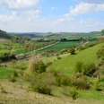 Blick von der Landschaftsliege Ottbergen Panoramablick über sanfte grüne Hügel, blühende Bäume und ein Weidegebiet bei Ottbergen, Niedersachsen.