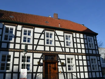 Haupteingang am Storck-Haus in Werther (Westf.) Fachwerkhaus mit rotem Ziegeldach und weißen Wänden, Fenster mit grünen Rahmen, blauer Himmel.
