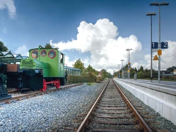 Alte Geha-Lok am Hövelhofer Bahnhof Eine historische grüne Geha-Lok steht auf Schienen am Hövelhofer Bahnhof, eingerahmt von Bäumen.