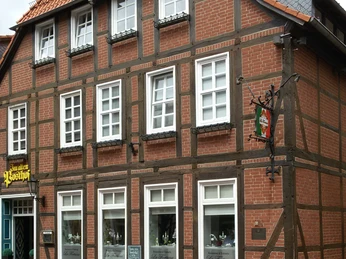 Zweistöckiges Fachwerkgebäude mit rotem Ziegeldach, repräsentative Fensterfront in historischer Optik.