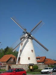 Wall-Holländermühle Dieckmann auf dem Gehlenbrink in Hücker-Aschen Historische Windmühle mit weißem Turm und Holzelementen, umgeben von Häusern und Bäumen unter blauem Himmel.