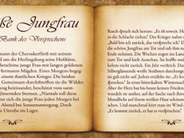 Geöffnetes Buch zeigt den Text über die Legende 'Die weiße Jungfrau', umgeben von Sonnenlicht und Schattenschrift.