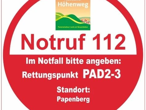 Rotes, rundes Rettungspunkt-Schild PAD2-3 am Papenberg, Notrufnummer 112, hilfreiche Notfallangabe.
