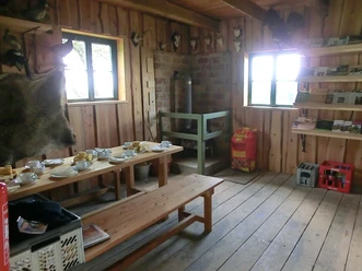Räumlichkeiten in der Waldschule Modexen Rustikale Holzausstattung in einem Raum mit Sitzbänken, gedecktem Tisch und dekorativen Jagdtrophäen.