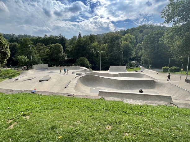 Wiehlpark Ein moderner Skatepark inmitten grüner Landschaft, mit Skatern auf den Rampen und bewaldeter Kulisse.