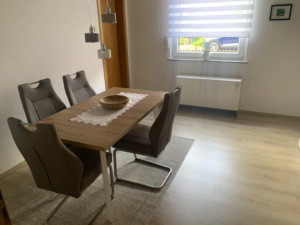 Esszimmer Esszimmer mit vier modernen Stühlen um einen Holztisch, Fenster mit gefiltertem Tageslicht.