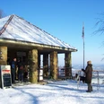 Winterliche Schwedenschanze mit schneebedecktem Dach, Besuchern und Blick auf die verschneite Landschaft.