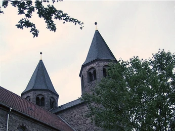 Kloster Bursfelde Zwei historische Kirchtürme des Klosters Bursfelde, umrahmt von grünem Laub und bewölktem Himmel.