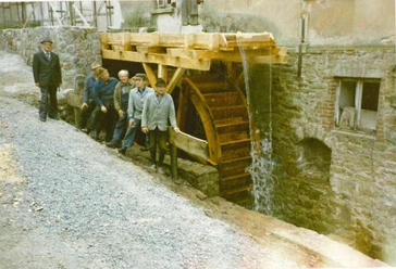 alte Mühle in Elbrinxen Fünf Männer posieren vor einem historischen Wasserrad an einer steinernen Mühle in Elbrinxen.