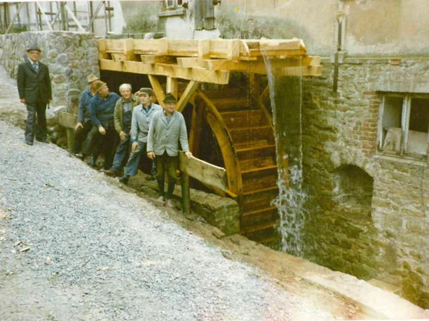 alte Mühle in Elbrinxen Fünf Männer posieren vor einem historischen Wasserrad an einer steinernen Mühle in Elbrinxen.