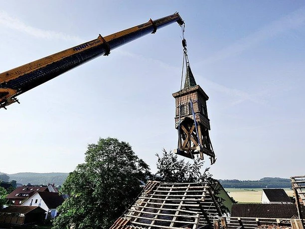 Abriss der alten Schule Ein Kran hebt einen baufälligen Schul-Glockenturm vor landschaftlicher Kulisse ab.
