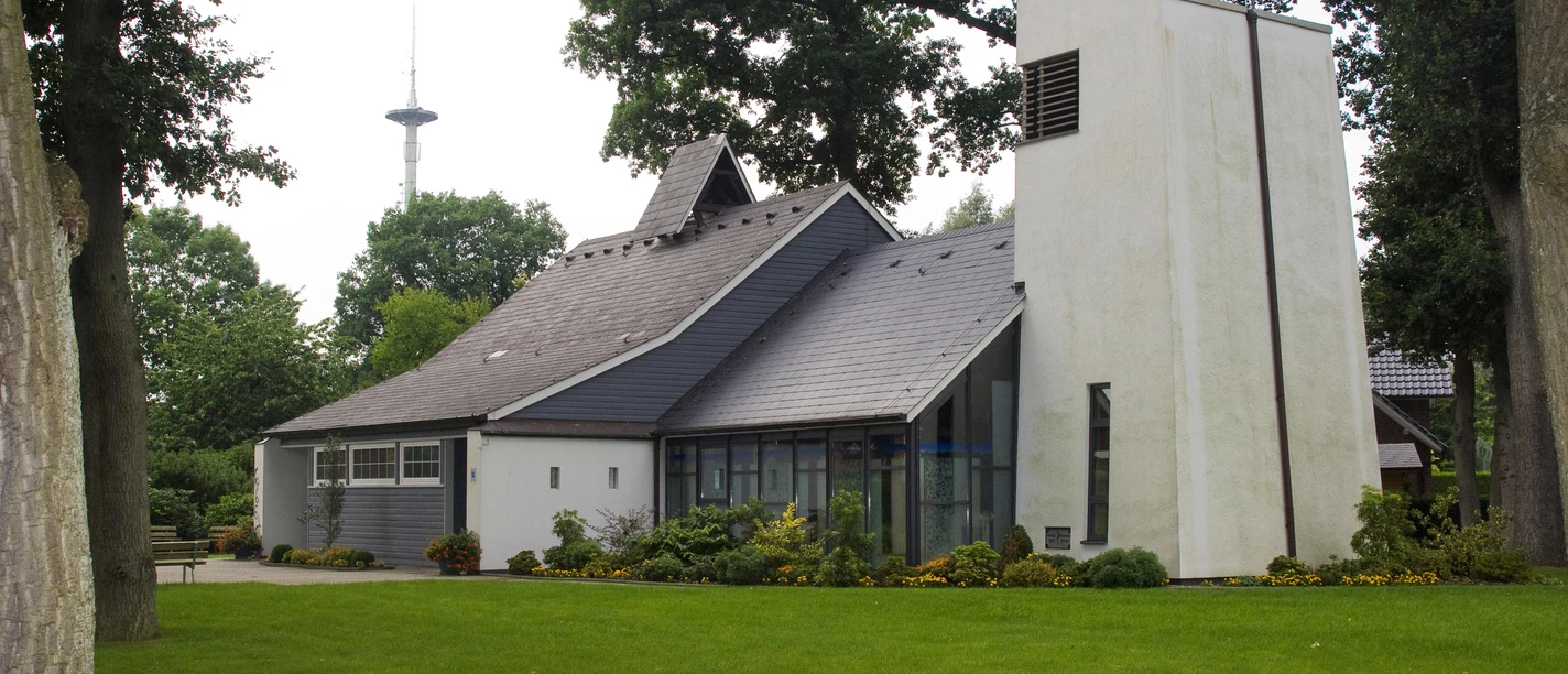 Evangelisch-lutherische St. Lukas Kirche Moderne Kirche mit schrägem Dach und hellem Turm, umgeben von Rasen und alten Bäumen in Werlte