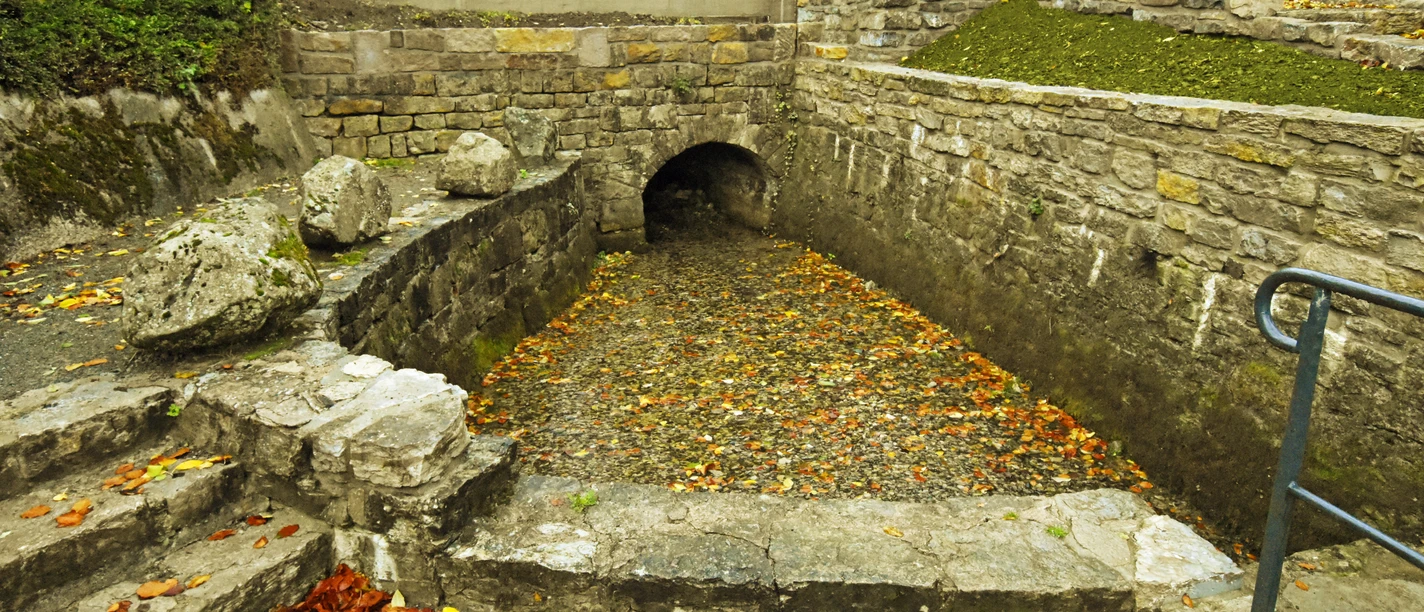 Nethequelle Neuenheerse Nethequelle in Neuenheerse: Historisches Quellbecken mit Herbstlaub, umgeben von Bruchsteinmauern.
