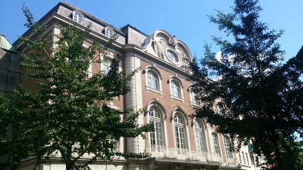 Altes Kurhaus Aachen Dreigeschossiges Gebäude im neoklassizistischen Stil, umgeben von grünen Bäumen und einem strahlend blauen Himmel.