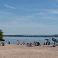 Der Badestrand in Mardorf, belebt und sonnig, lädt ein zum Entspannen am klaren, ruhigen Wasser.