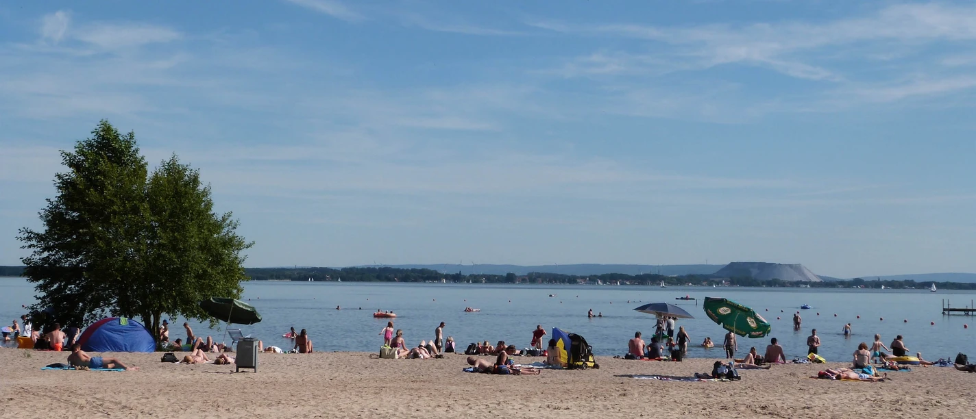 Het strand in Mardorf, levendig en zonnig, nodigt je uit om te ontspannen in het heldere, rustige water.