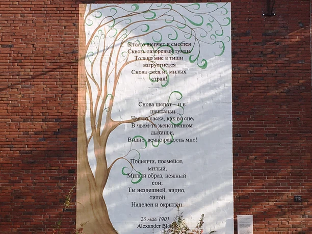 3. Mauergedicht - Turnhalle am Waldbald, Sögel Gedicht in russischer Sprache auf weißem Wandbild mit Baum-Motiv an roter Backsteinwand der Turnhalle.