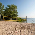 beach-volleyball Ein heißer Sommertag am See, ein Beachvolleyballfeld im Sand eingerahmt von grünen Bäumen.