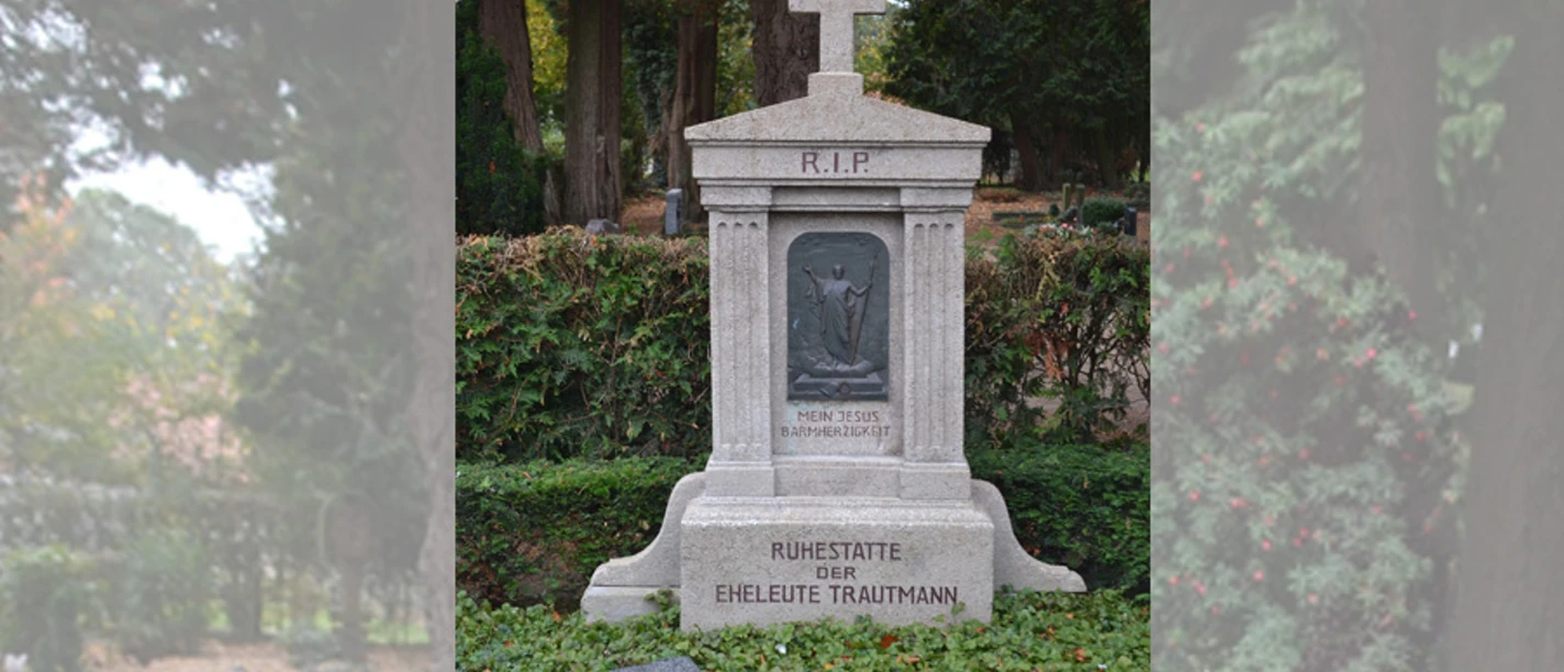 Grabstätte Albert Trautmann Steinerne Grabstätte der Eheleute Trautmann mit Kreuz und Christusrelief auf ruhigem Friedhof.