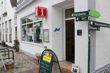 Tourist-Information Meldorf Eingang der Tourist-Info mit Wegweisern am Gebäude