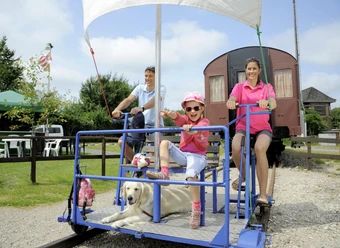 Marschenbahn-Draisine Marne Familie fährt Draisine mit Hund auf Gleis