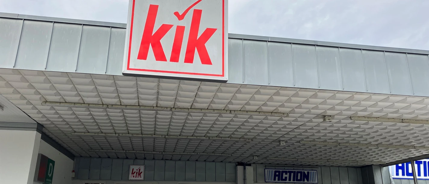 KiK-Filiale mit großem Logo über dem Eingang und Kleiderständern vor der Ladenfront