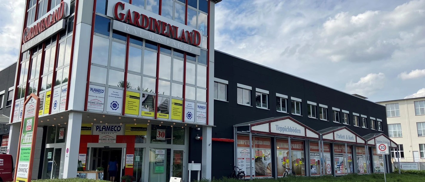 Fassade des HOME-STORE Gardinenland mit großen Glasfronten an einer Straße
