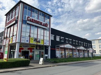 Fassade des HOME-STORE Gardinenland mit großen Glasfronten an einer Straße