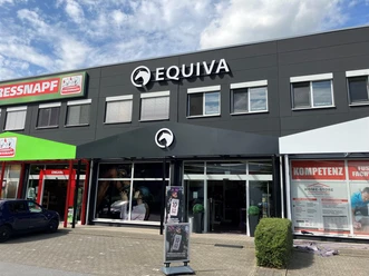 Außenansicht der Equiva-Filiale mit schwarzer Fassade und Nachbargeschäften
